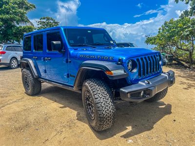 The blue High Tide parked on open sandy ground under a bright sky