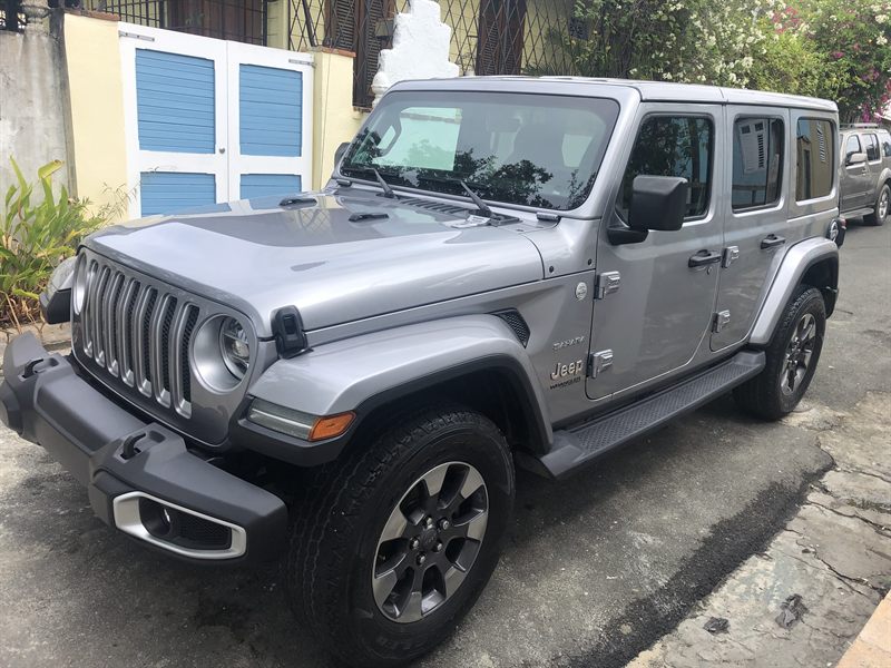Silver Jeep Wrangler Unlimited Sahara with body-color hardtop, parked on a street in Vieques
