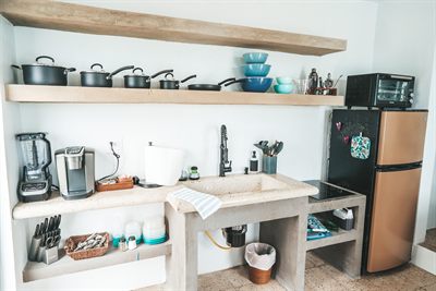 Kitchen with open timber shelving stacked with pans and bowls, and a brass-fronted fridge