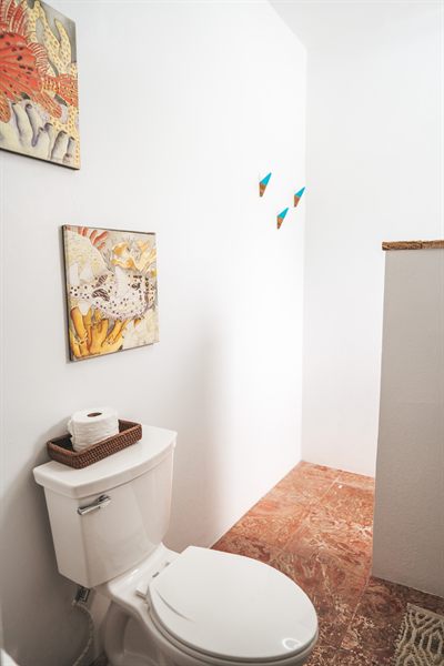 Bathroom with coral-themed artwork above the basin and a terracotta tiled floor