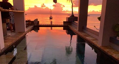 The cocktail pool at sunset, the sky and a sailboat reflected in the still water