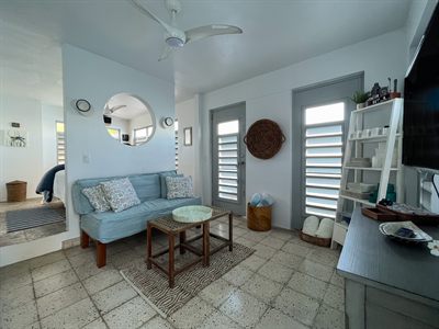 Sitting room with a pale blue sofa, round mirror, woven wall basket and louvered doors