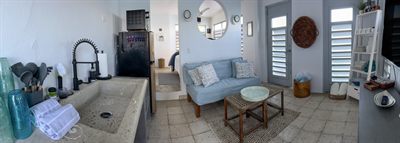 Panorama of the kitchen and living area with sofa, coffee table and louvered doors