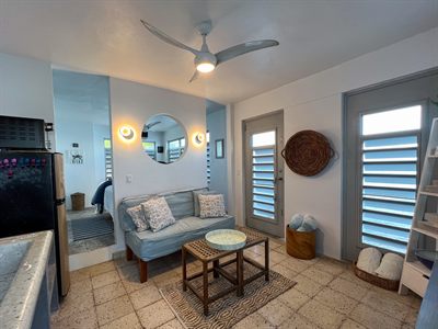 Living area seen from the kitchen, with the sofa, mirror and louvered doors