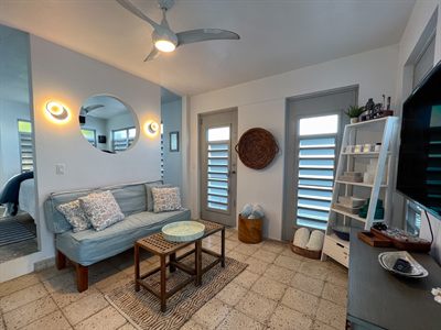 Blue sofa beneath a round mirror, with a woven wall basket and louvered doors either side