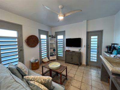 Living room with a television on a gray sideboard, louvered doors and a woven wall basket