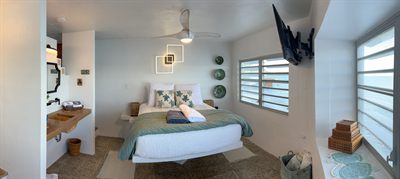 Queen bedroom with a teal throw, decorative plates and an ensuite vanity to the left