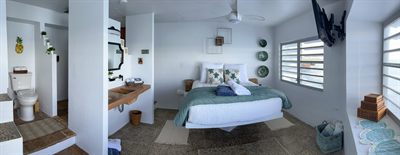 Panorama of a bedroom and its ensuite, with a queen bed and marlin sculpture above the window