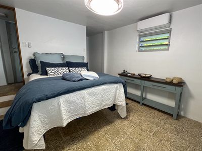Bedroom with navy bedding and a pale teal console table beneath a louvered window