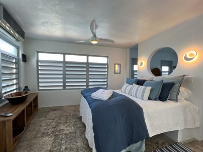 Bedroom with navy bedding, a round mirror between wall sconces and a low timber bench