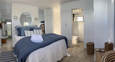 Wide view of a bedroom with navy bedding and its ensuite bathroom beyond