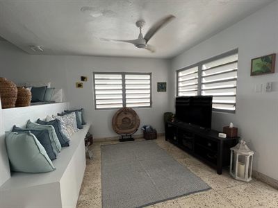 Lounge with built-in banquette seating, scatter cushions, a television unit and woven wall art