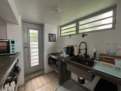 Kitchenette with a concrete counter and sink, coffee maker and a framed Puerto Rican flag