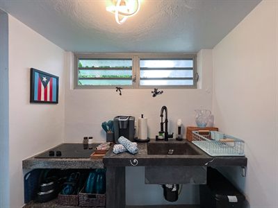 Kitchenette counter with kettle, coffee maker and drying rack under louvered windows