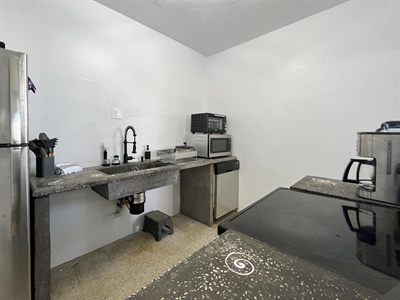 Kitchen with a concrete counter, sink, microwave and stainless fridge