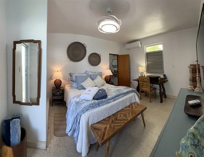 Bedroom with a queen bed, woven wall discs, a writing desk and a mirrored wardrobe