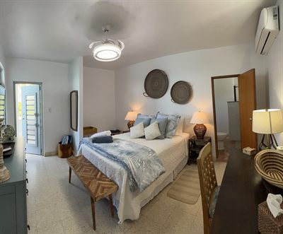 Queen bedroom with woven wall discs above the bed and a timber bench at its foot