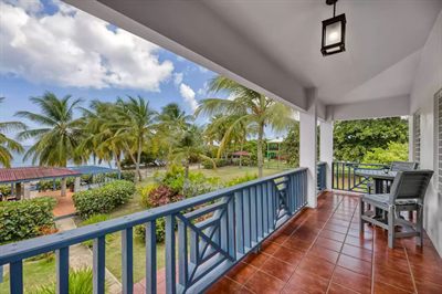 The upstairs balcony at Media Luna, terracotta tile and blue railings looking over the garden to the water