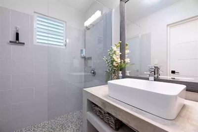 Bathroom with a glass walk-in shower, pebble floor and a vessel basin on a concrete counter