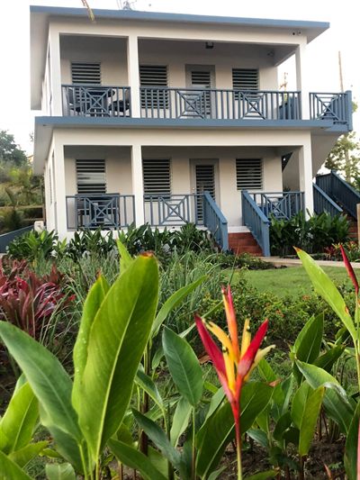 The two-story casitas seen from the garden, each floor with its own balcony and staircase, heliconia flowering in front