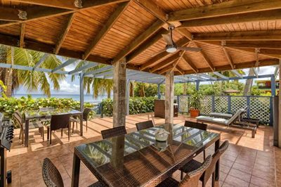 Inside the beachfront gazebo, with a timber-beamed roof, dining tables and loungers facing the sea