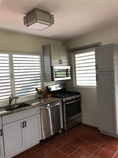 Kitchen with a stainless gas range, microwave and dishwasher, granite counters and louvered windows
