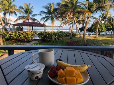 Breakfast of fruit, yogurt and coffee on the patio table, the gazebo and sea beyond