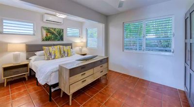 Bright Sun Bay bedroom with an upholstered headboard, botanical prints and terracotta tile