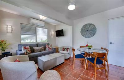 Sun Bay living room with a gray sofa, armchairs and a round dining table with blue and timber chairs