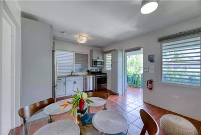 Sun Bay's open-plan living and dining area with a glass table, stainless kitchen and a door to the lanai